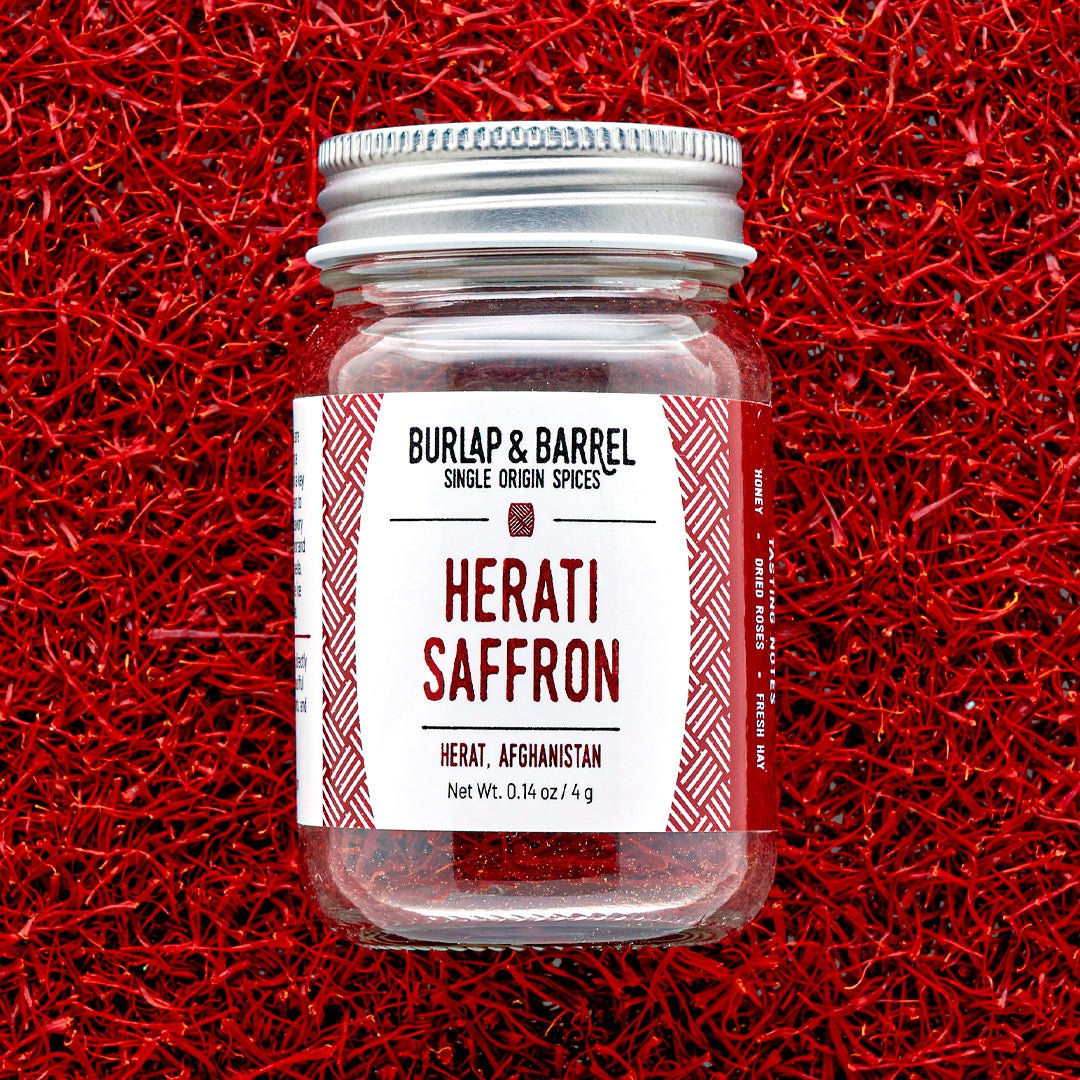 Burlap & Barrel Herati Saffron from Herat, Afghanistan in glass jar with silver lid on red background