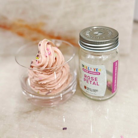  Photo By Rachel Schwartz .A jar of Molly Yeh Spiced Sprinkles in Rose Petal sits next to a glass dish of swirl-topped pink frosting or soft-serve dessert decorated with colorful sprinkles