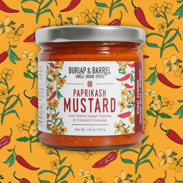 Burlap & Barrel Paprikash Mustard jar with Noble Sweet Paprika & Crescent Caraway on yellow floral and chili background