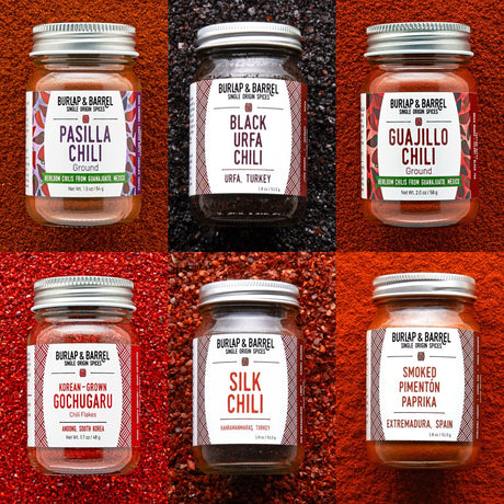 Jars of Burlap & Barrel chilis on multi-colored background of loose chili flakes