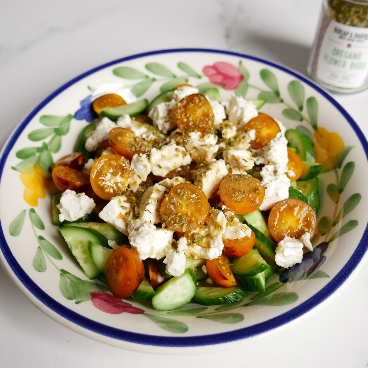 Salad with tomatoes, cucumbers, and feta cheese on a decorative plate.