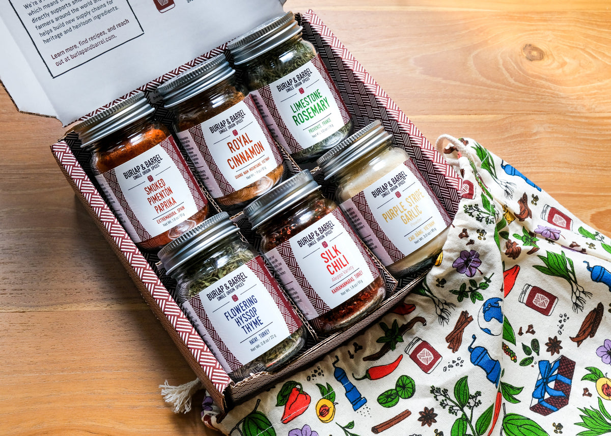 Box of spice jars on a wooden surface with a patterned cloth underneath