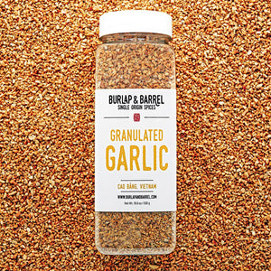 Jar of granulated garlic from Burlap & Barrel on a bed of granulated garlic.