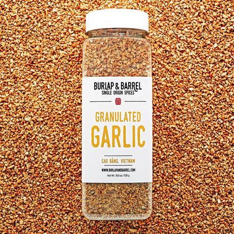 Jar of granulated garlic from Burlap & Barrel on a bed of granulated garlic.