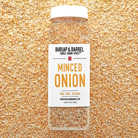 Jar of minced onion spice with Burlap & Barrel label on a textured gold background