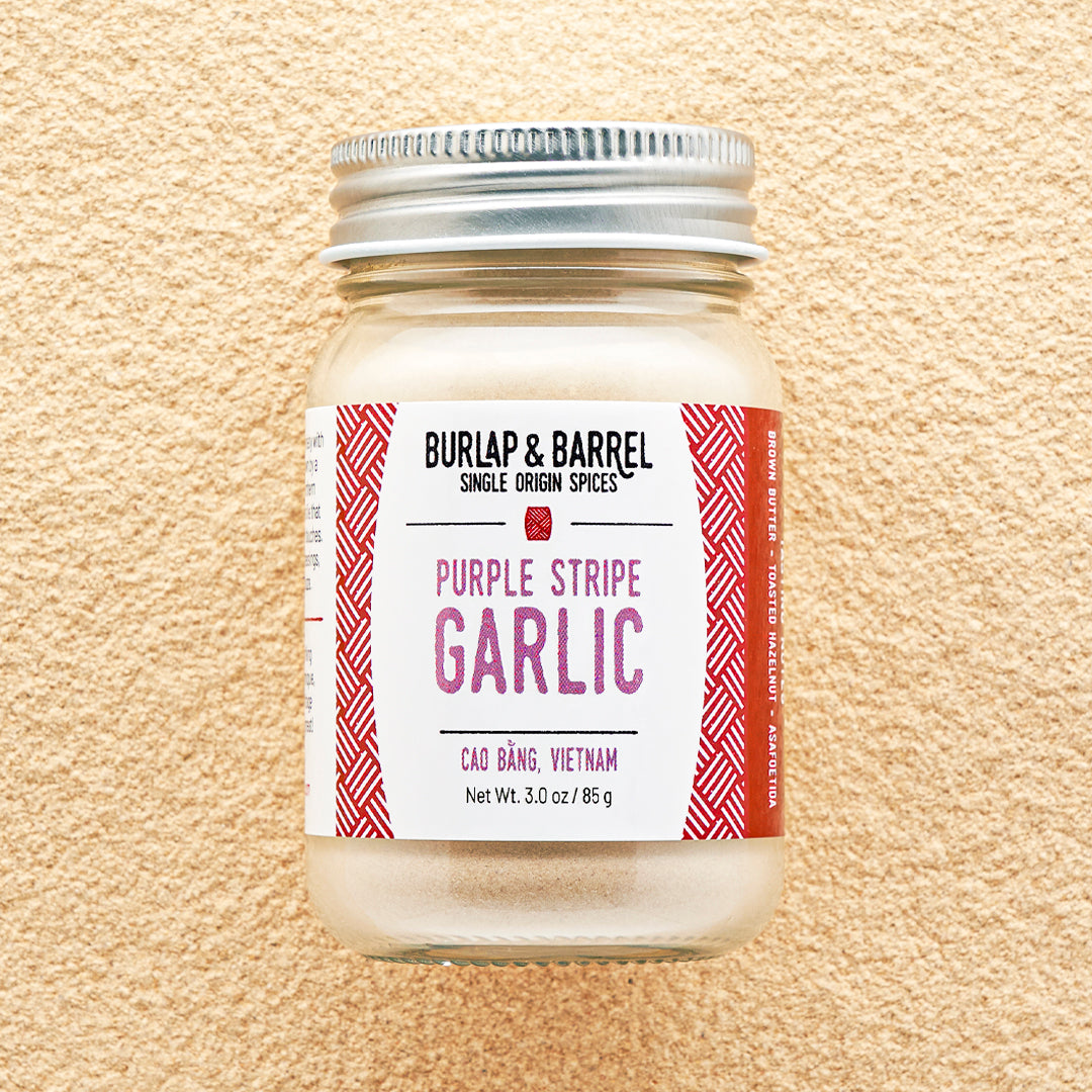 Jar of Purple Stripe Garlic from Burlap & Barrel on a beige background