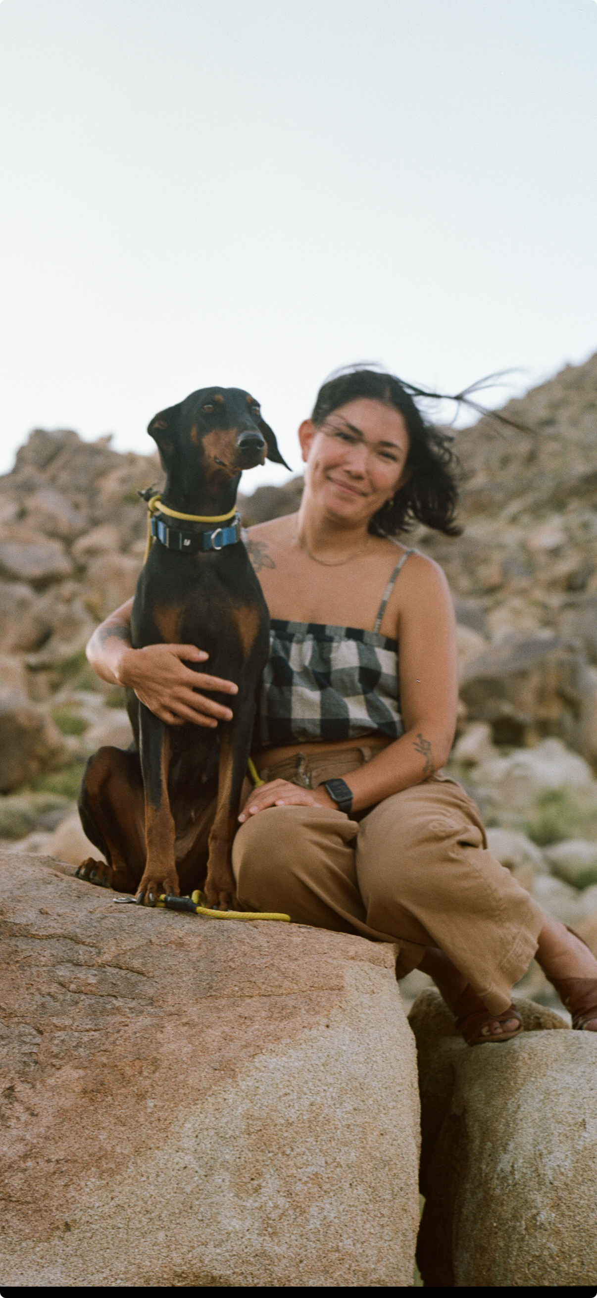 Woman sitting on a rock with a dog in a desert-like setting