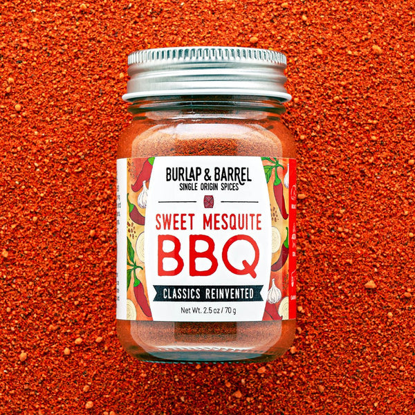 Jar of Burlap & Barrel Sweet Mesquite BBQ spice blend on a red background