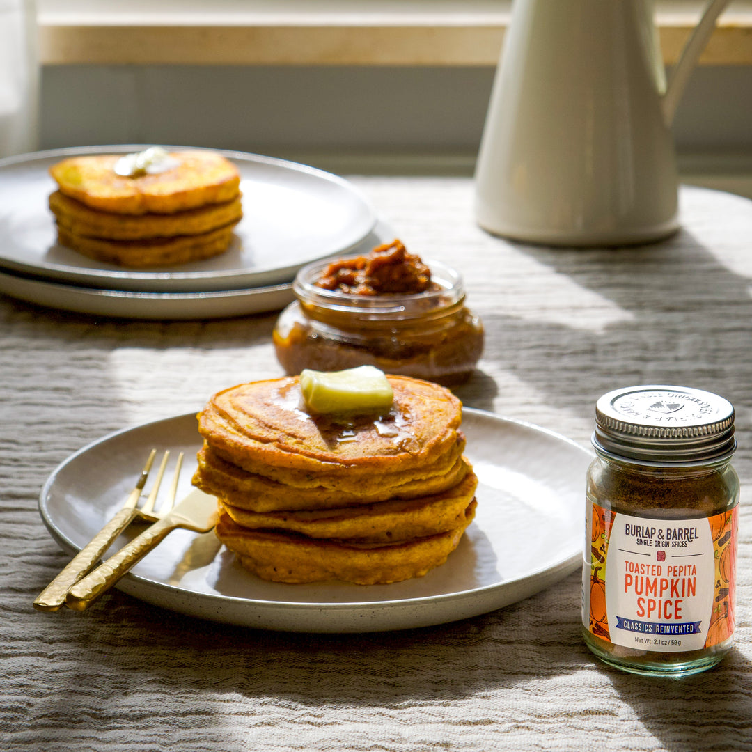 Stack of pumpkin pancakes with a jar of Toasted Pepita Pumpkin Spice from Burlap & Barrel 