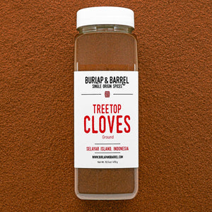 Container of Burlap & Barrel Treetop Cloves on a brown background