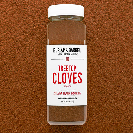 Container of Burlap & Barrel Treetop Cloves on a brown background