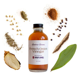 Lindera Farms French Onion Vinegar bottle surrounded by ingredient components including onion, herbs, spices, and juniper berries.