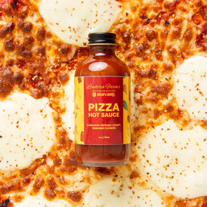 Lindera Farms Pizza Hot Sauce bottle on pepperoni pizza background with red and yellow label featuring Burlap & Barrel branding
