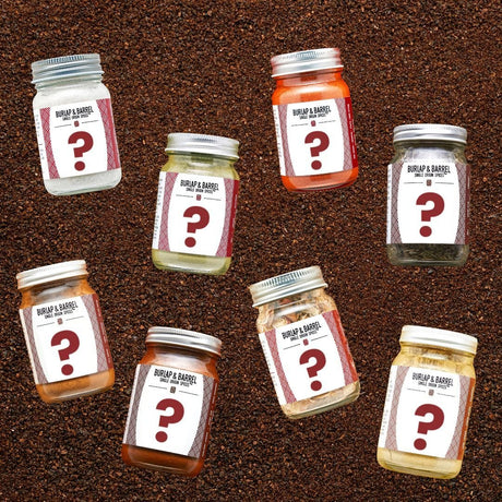A collection of full-sized jars of spices with mystery labels, arranged on a bed of loose spices.