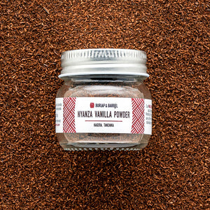 Burlap & Barrel Nyanza Vanilla Powder jar with silver lid on brown textured background