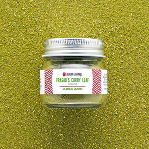 Burlap & Barrel Prasad's Curry Leaf Ground spice jar with silver lid on green textured background